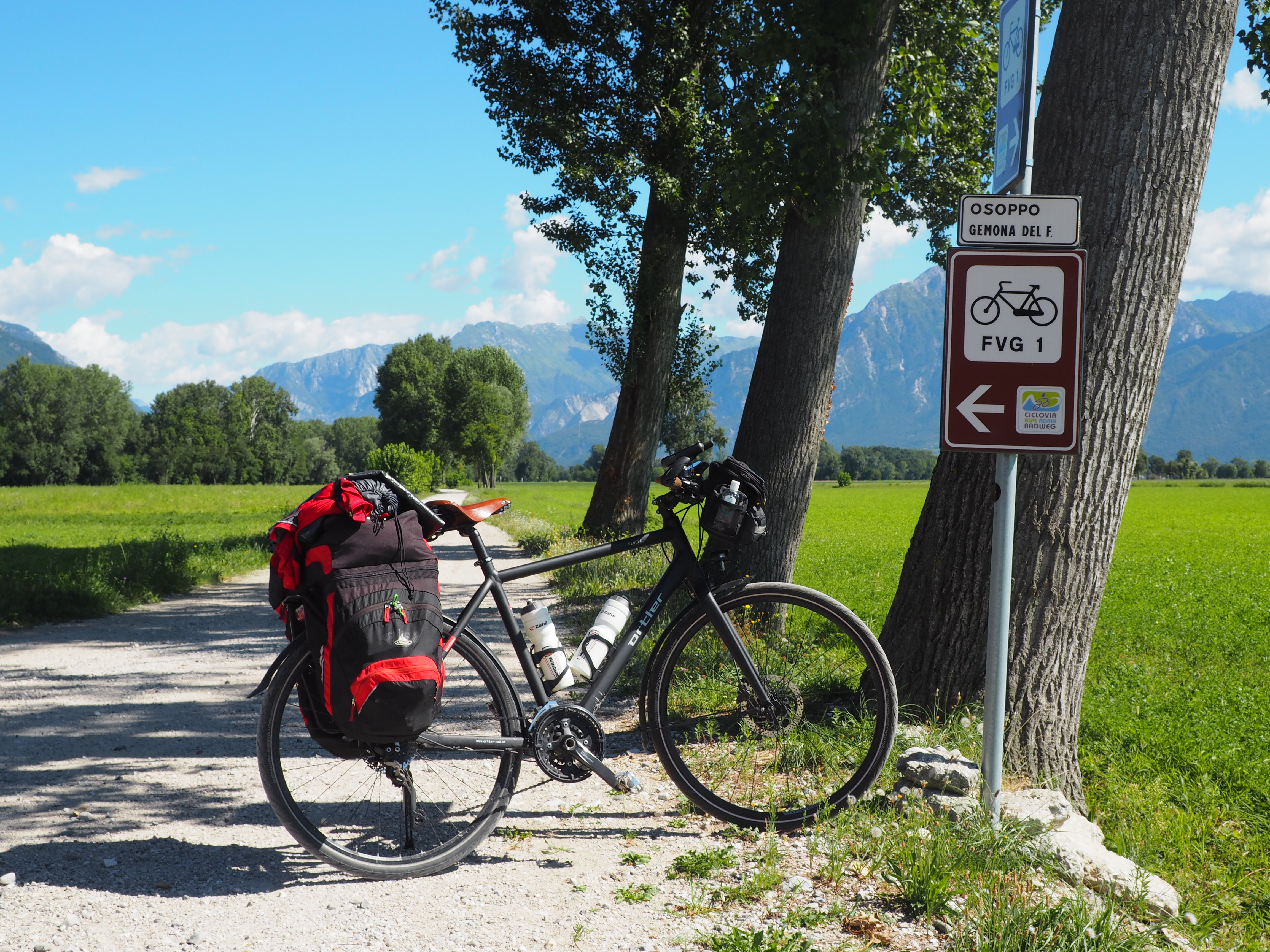 Bici carica da viaggio lungo la ciclovia FVG 1, fra campi e montagne del Friuli